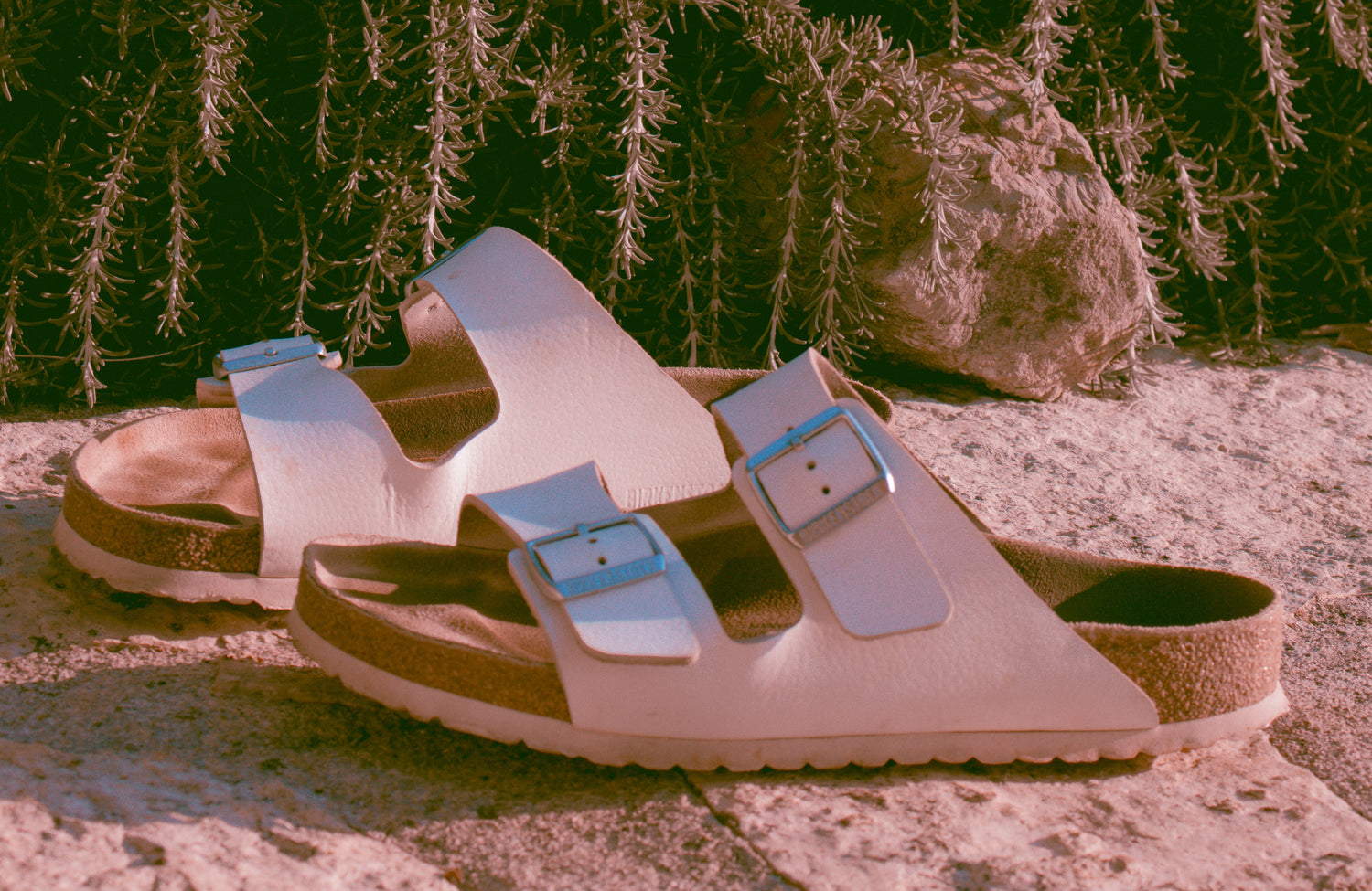 two white arizona birkenstock sandals on sand