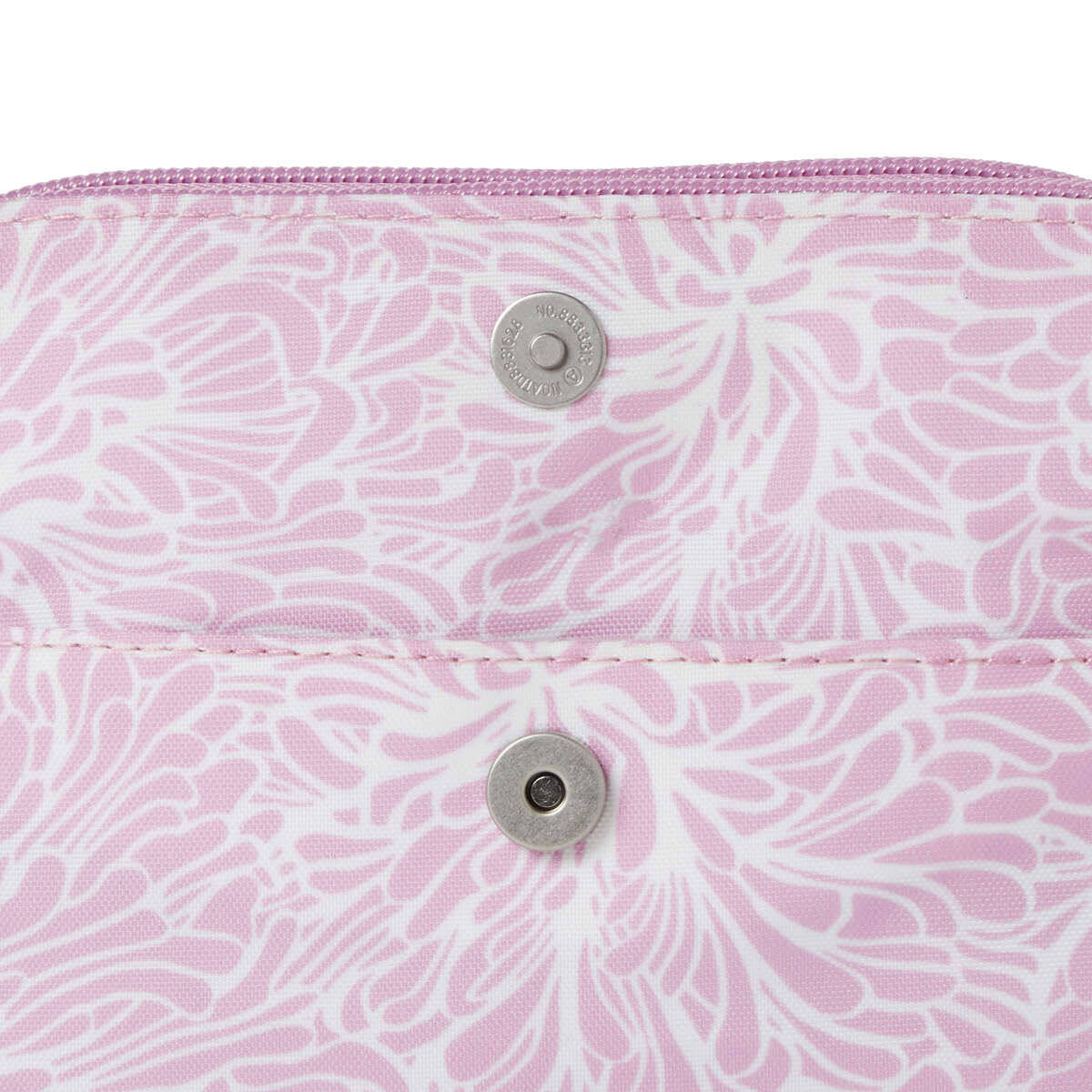 close up view of magnet snaps of baggallini modern everywhere mini bag in pink blossom color